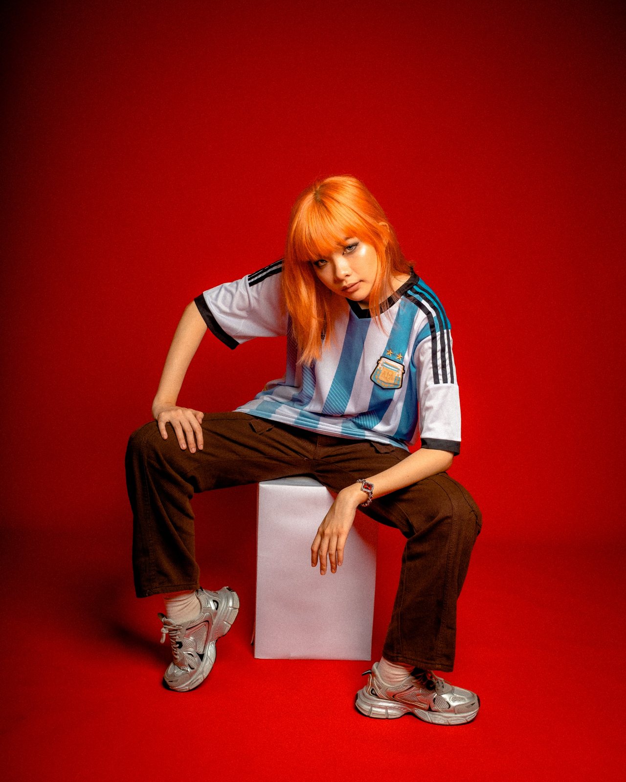 Editorial campaign, red backdrop, seated on white block