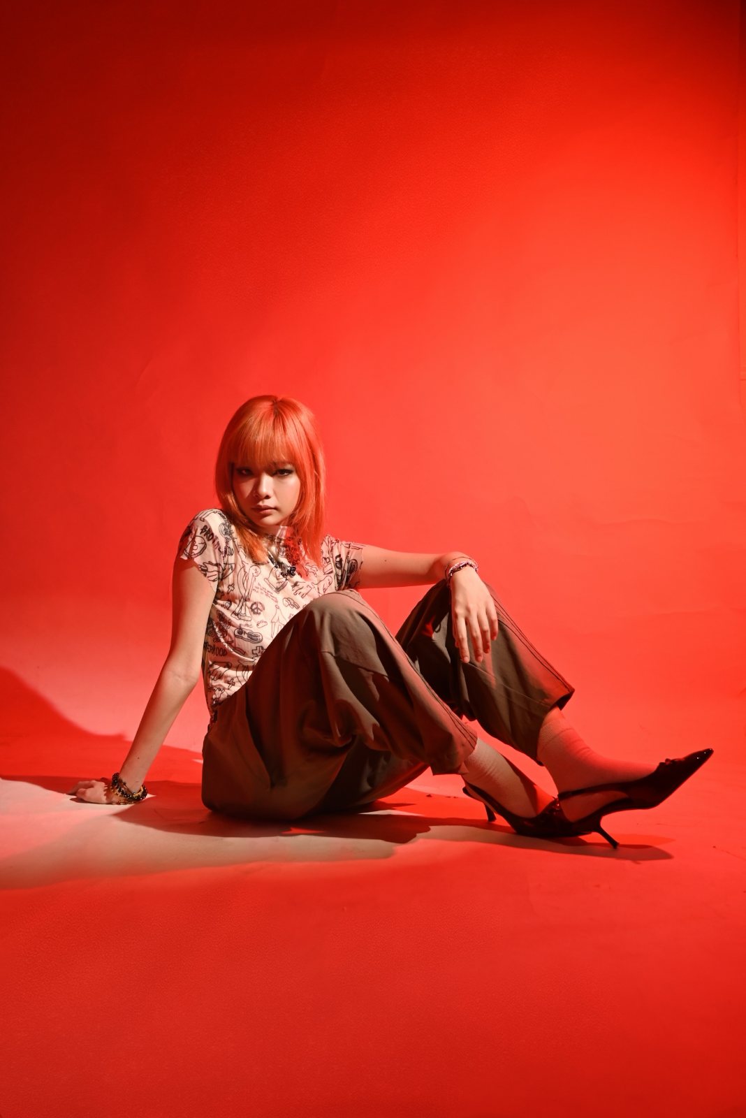 Editorial campaign, red backdrop, seated with heels