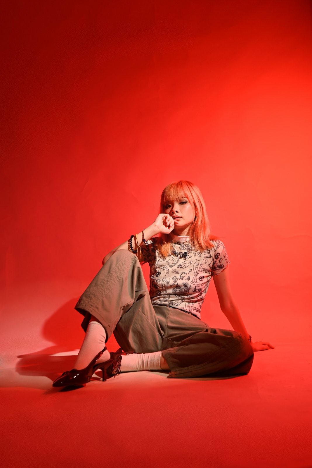 Red backdrop portrait, seated, hand at chin