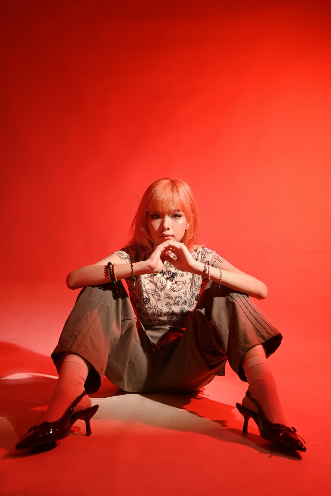 Red backdrop portrait, seated, hands together