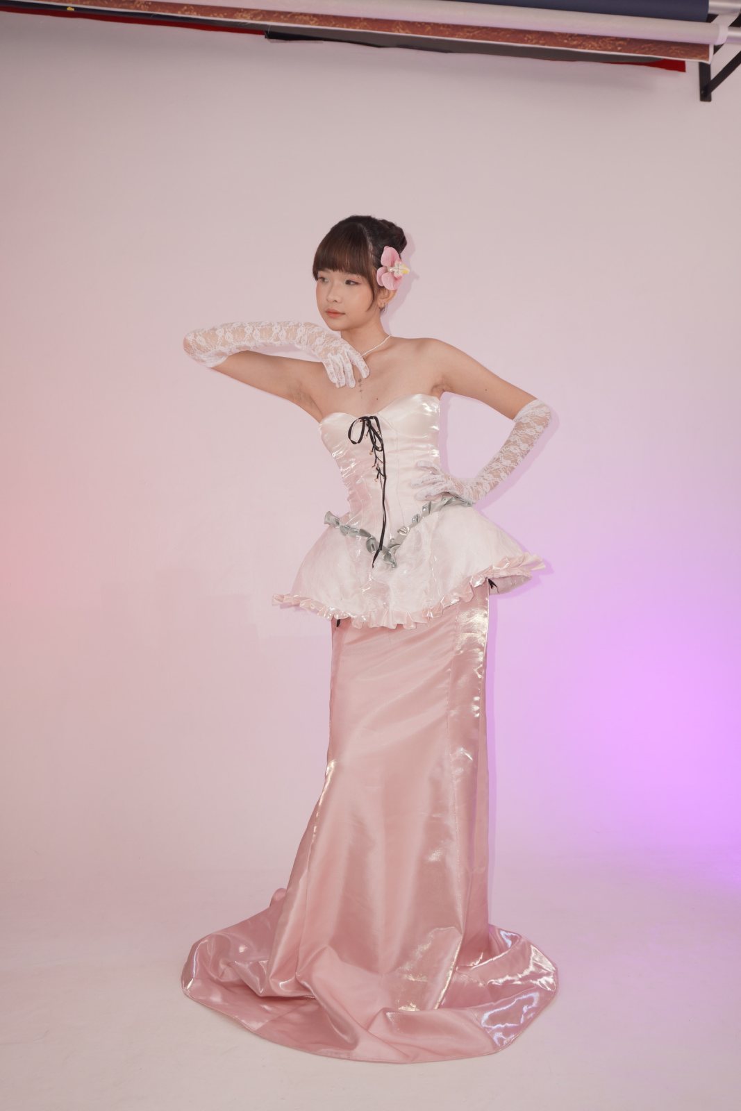 Full-length pose on set, gloved arm raised