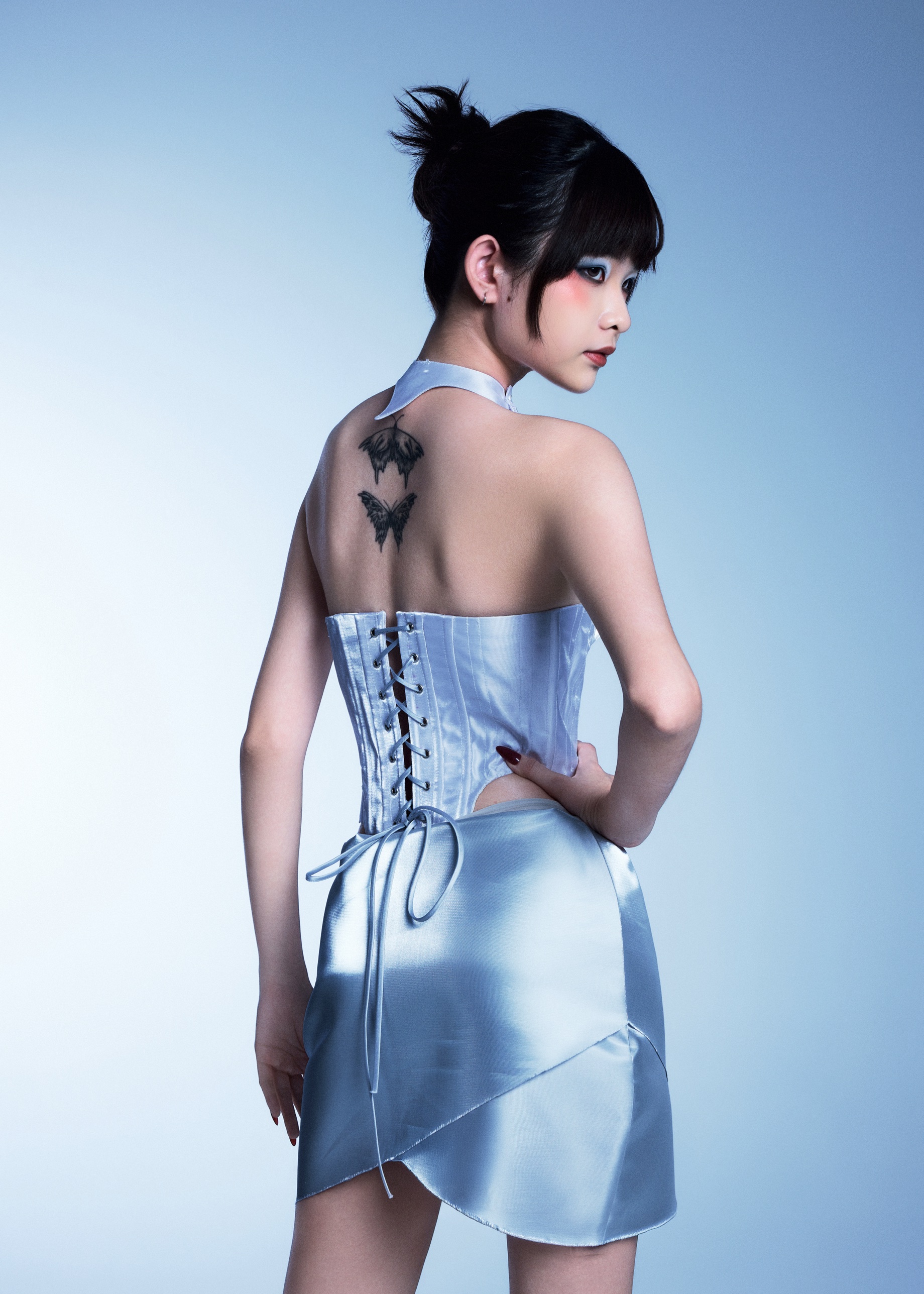 Back view: corset lacing and butterfly tattoos, looking over the shoulder