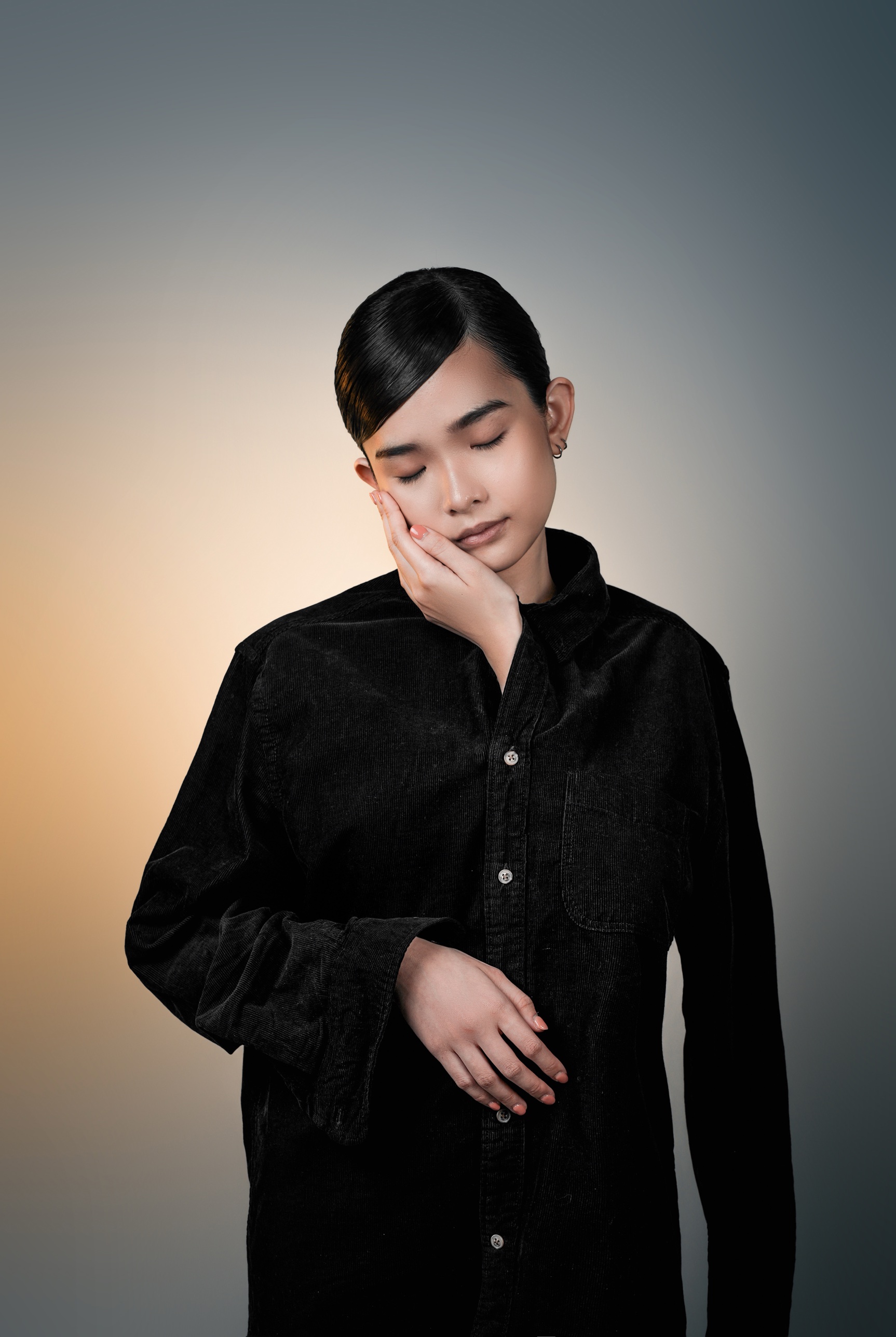 Eyes closed, hand on cheek, black corduroy shirt