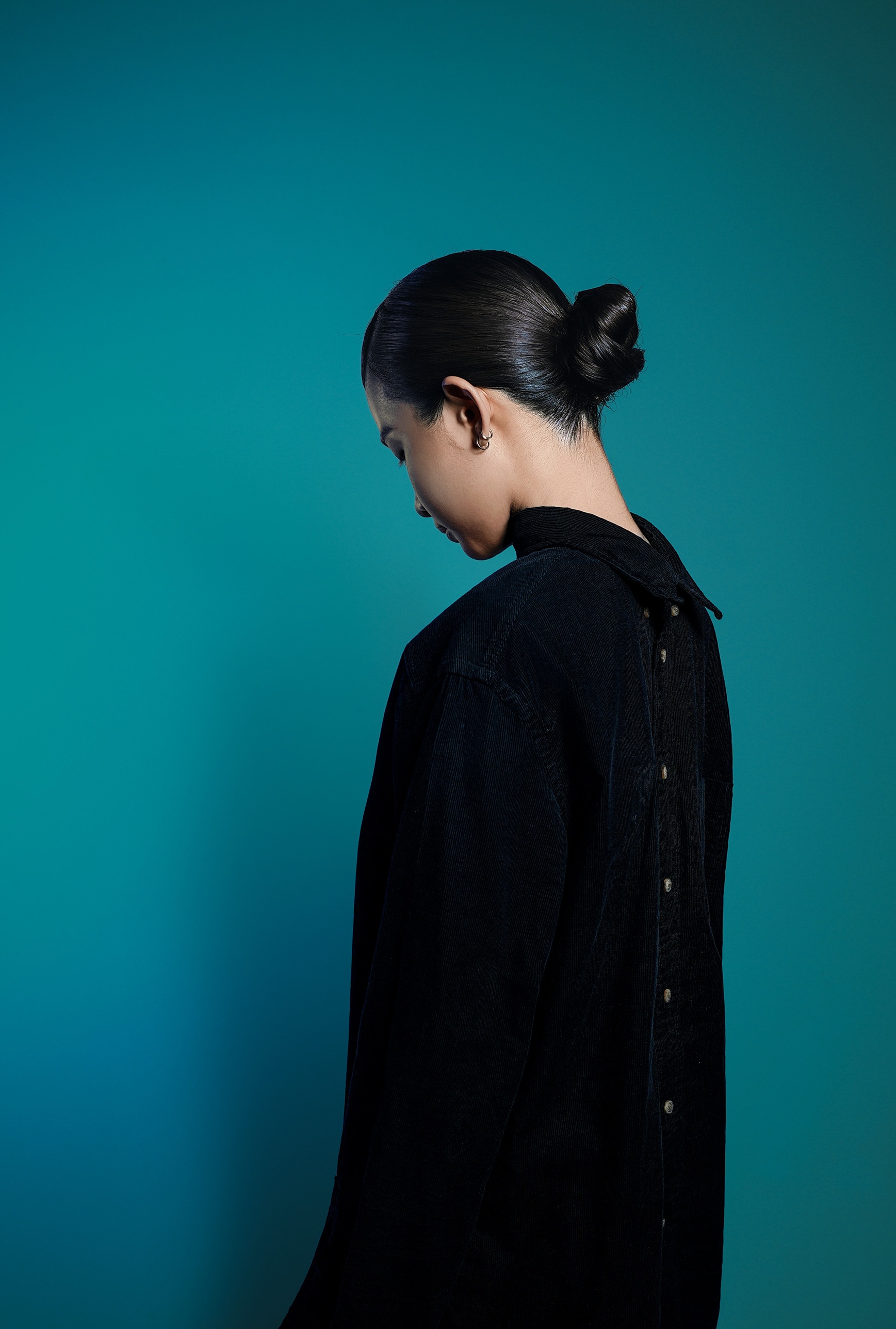 Looking down, slicked bun, teal backdrop