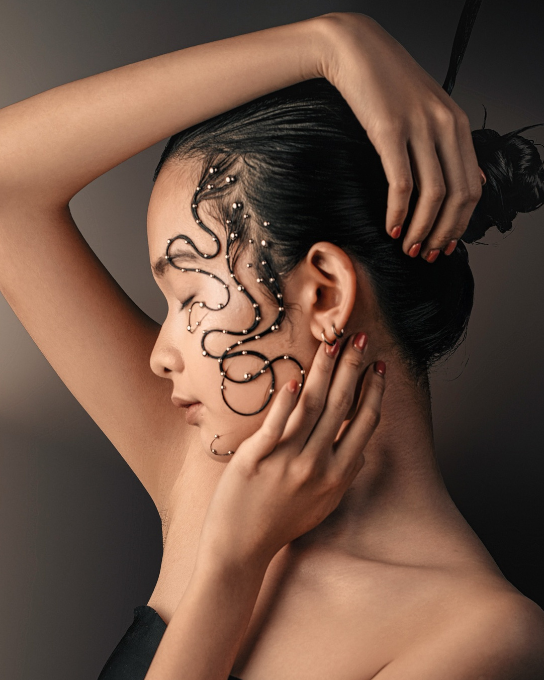 Profile, arm raised, beaded hair art across the face