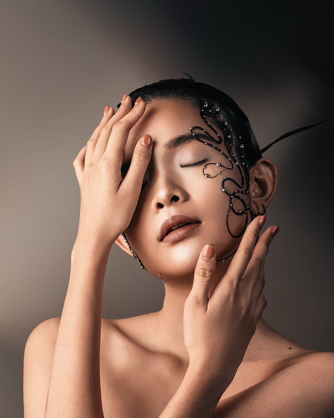 Eyes closed, hand over one eye, beaded hair art