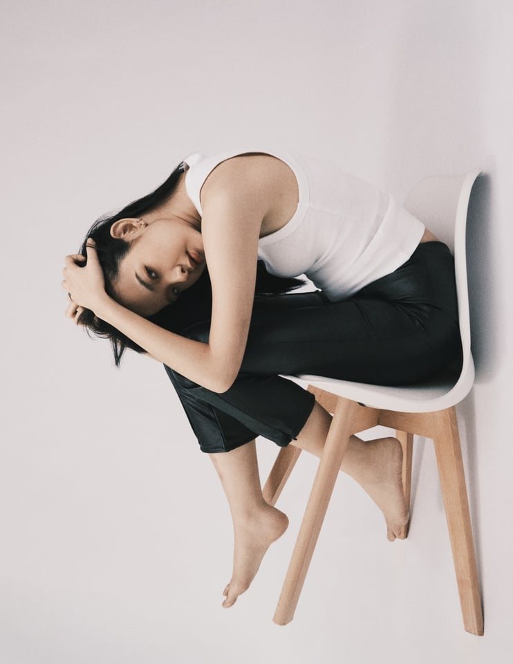 Curled on a white chair, shot sideways