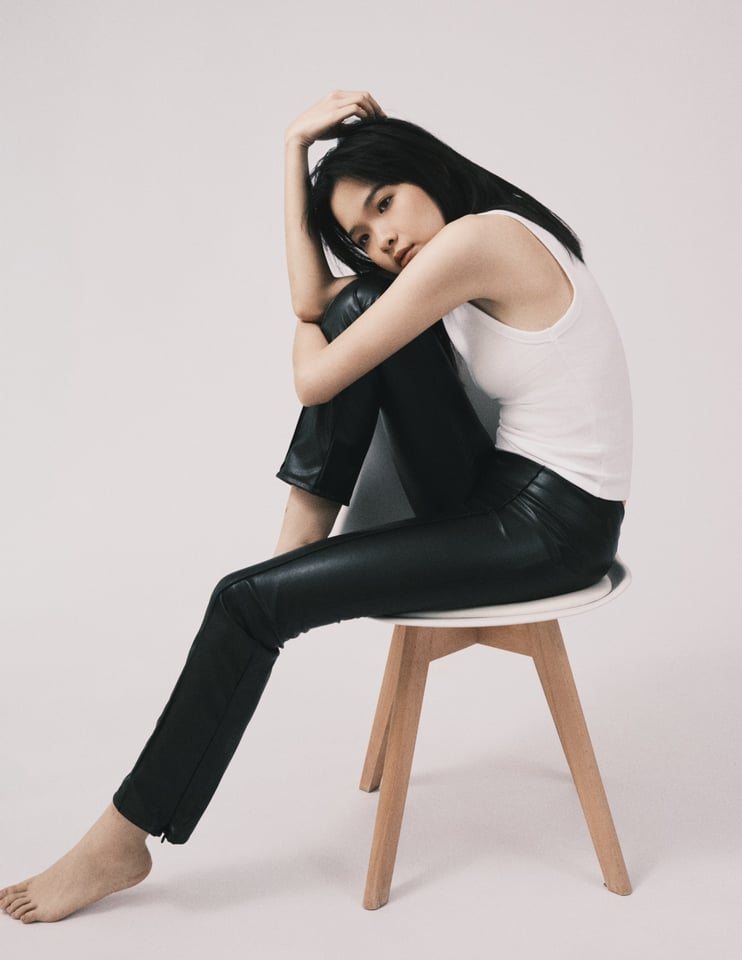 Seated on a stool, hugging knees
