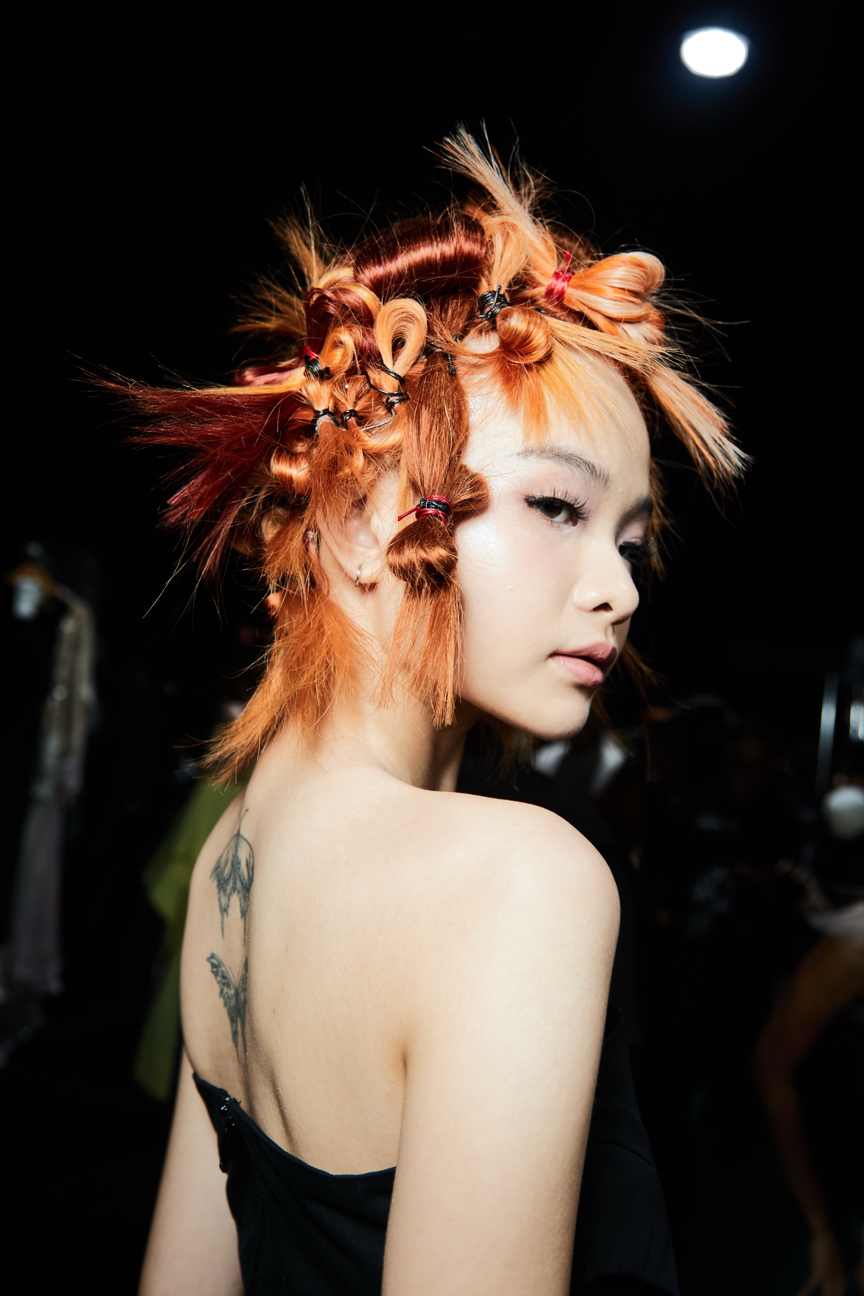 Backstage at KLFW: copper hair sculpted with knots and wire, looking over the shoulder