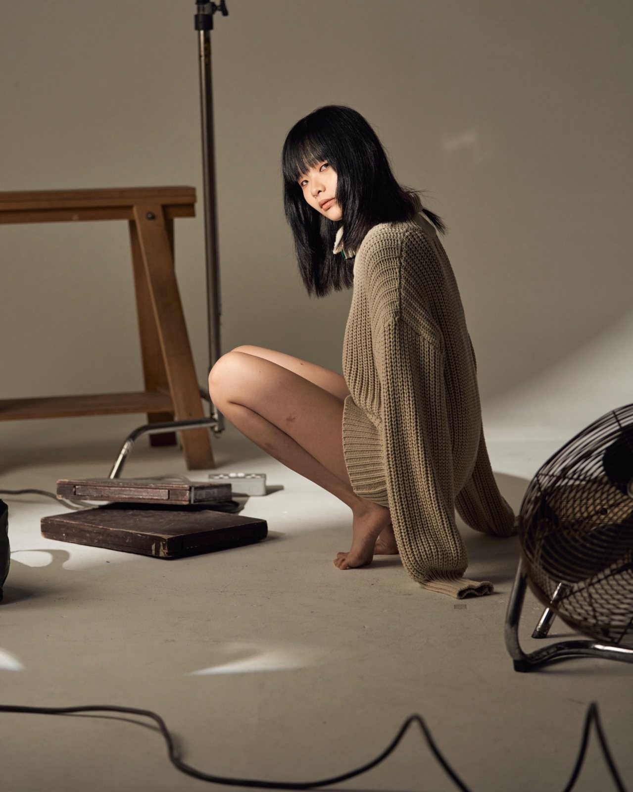 Studio portrait, knit sweater, crouching on studio floor