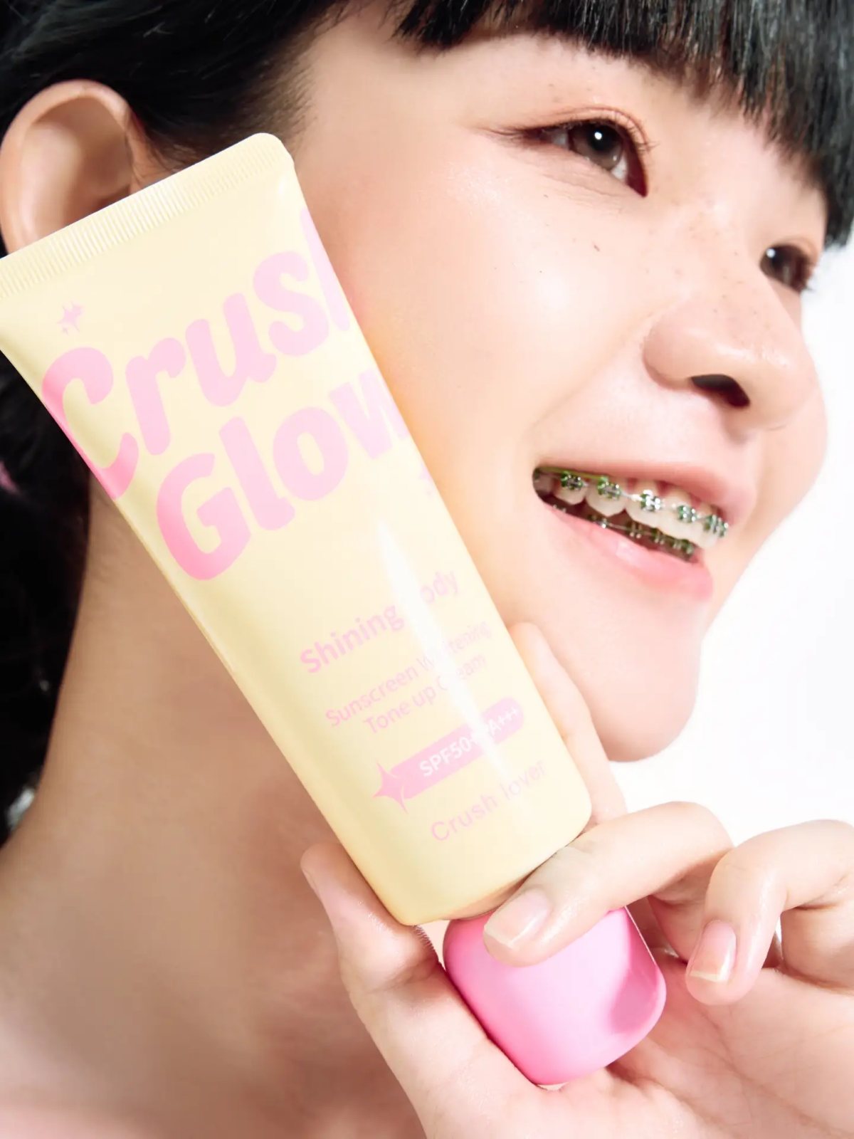 Sunscreen campaign, tube against cheek, smiling