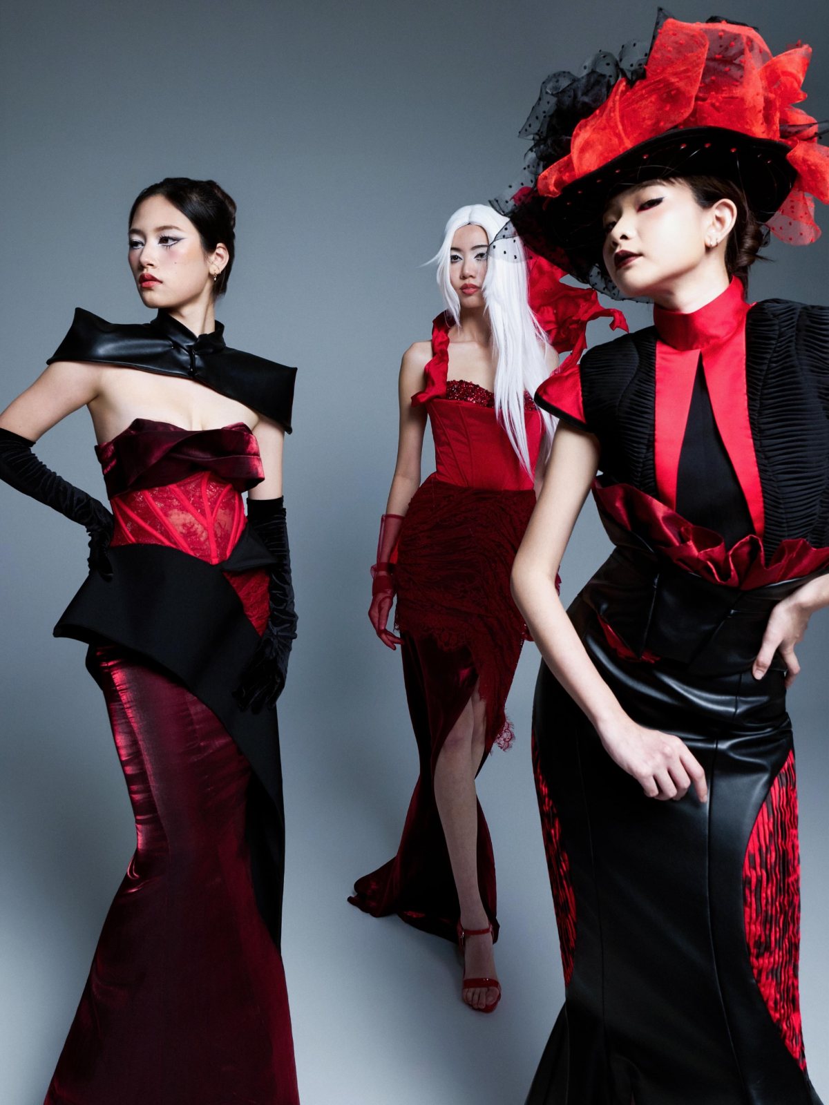 Three gowns in red and black, feathered hat in front