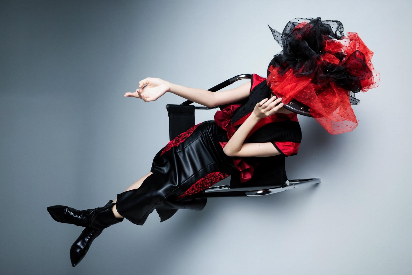 Reclining on a chrome chair under a tulle hat, shot from above